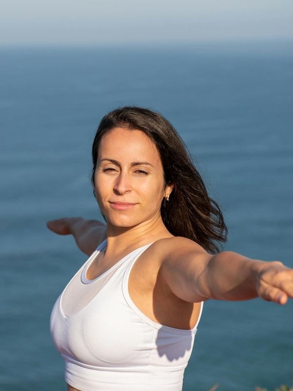 Person doing a powerful warrior yoga pose against a blue sky.
